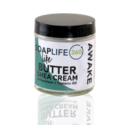 A jar of Awake Shea Butter Cream with a label that includes the brand name 'SOAPLIFE360' and the product name 'AWAKE'. The jar is clear, showcasing the white cream inside, and it has a black lid.